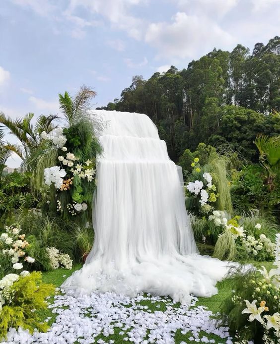 Decor đám cưới ngoài trời với backdrop voan nghệ thuật kết hợp hoa tươi và cây xanh, tạo không gian wedding outdoor đầy cảm xúc.
